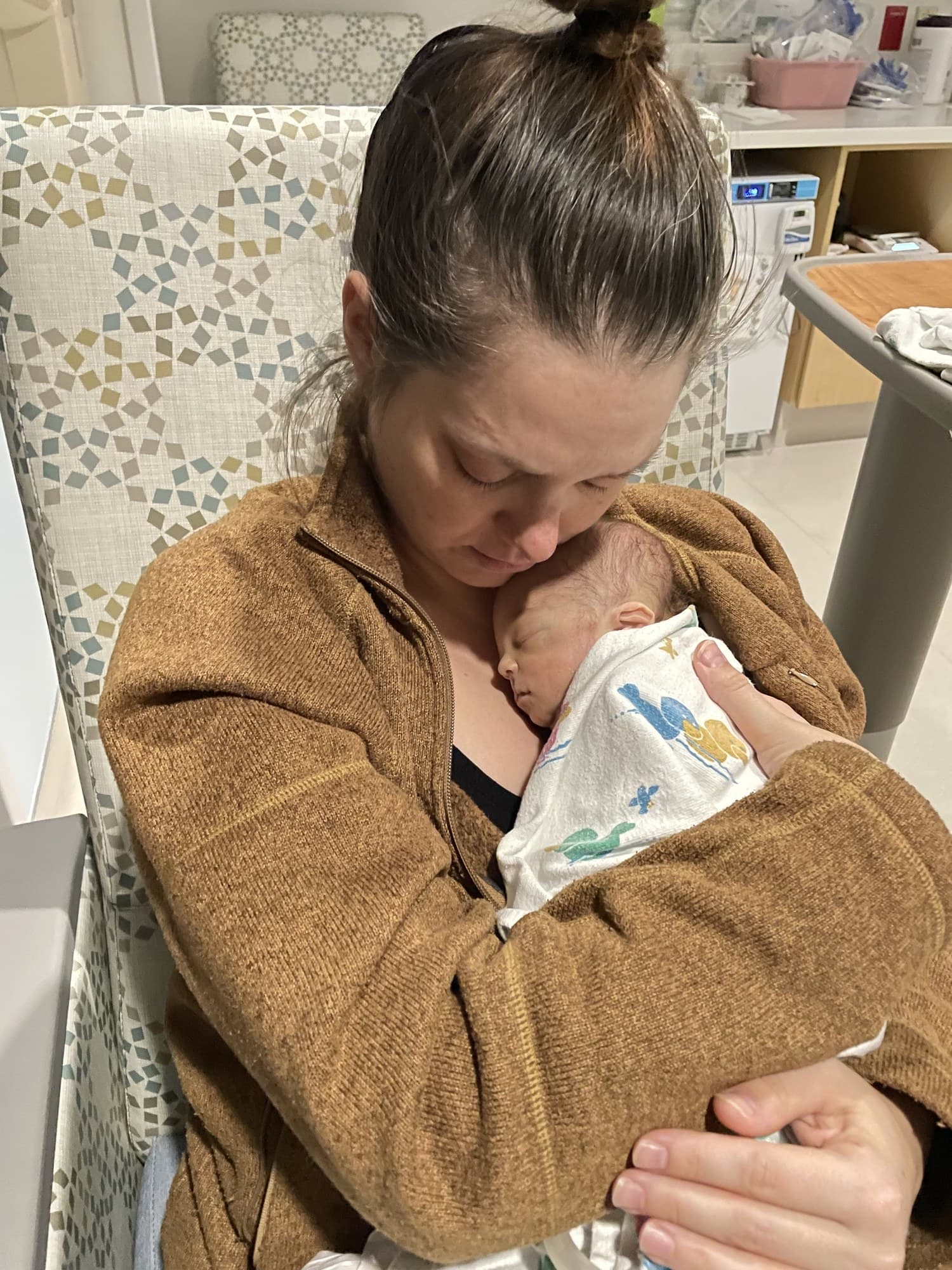 Liam's mom holding him close against her chest in a hospital room