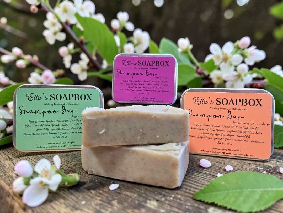 Shampoo bars in pink and green tins among white blossoms